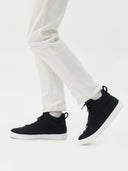 Black high-top sneakers worn with white pants on a light gray background #color_black