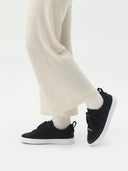 side view of black cashmere sneakers with white pants  #color_black