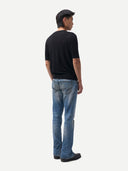 back view of a person wearing a black t-shirt and blue jeans on a white background #color_blue-graphite
