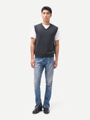 Man wearing a dark gray v-neck vest over a white shirt with blue jeans on a white background. #color_charcoal