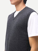 close up of a man wearing a gray knitted v-neck vest over a white shirt on a light gray background. #color_charcoal