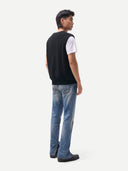 Back view of a person wearing a black sweater over a white shirt and blue jeans on a white background #color_black