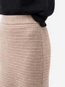Beige knitted skirt worn with a black sweater on a white background #color_fog