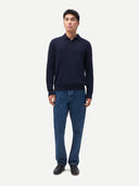 Man wearing a navy long-sleeve polo shirt and blue jeans on a white background. #color-navy