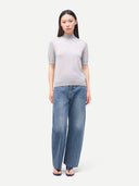 Woman wearing a gray short-sleeve mock sweater and blue jeans on a white background #color_vapor-blue