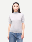 Woman wearing a gray turtleneck short-sleeve sweater and blue jeans on a white background #color_vapor-blue