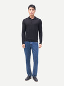 Man wearing a black long-sleeve shirt and blue jeans on a white background.