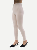 Close up side view of beige leggings, black heels worn by a woman  on a white background #color_whisper-white