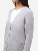 A close-up side view of a woman wearing a light gray knit cardigan over a white top, against a plain light background.