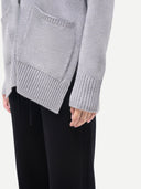 Gray knitted sweater worn by a person on a white background.