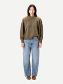 Person wearing a green sweater and blue jeans on a white background #color_aloe