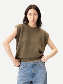 Woman wearing a sleeveless olive green sweater and blue jeans on a white background #color_aloe
