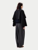 Back view of a person wearing a black cape and gray pants on a white background. #color_black
