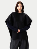 Person wearing a black poncho over a dark outfit on a white background #color_black