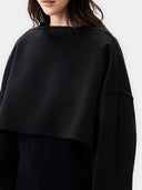 close up of a black poncho worn by a person on a white background #color_black