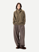 front view of a person wearing a green sweater, scarf and brown pants on a white background. #color_aloe