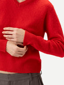 Close up of a red sweater worn by a person on a white background #color_fiery-red