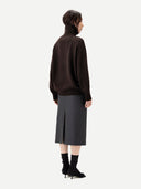 Back view of a person wearing a brown sweater and gray skirt on a white background #color_mole