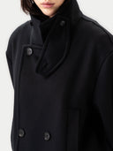 Close-up of a black coat with a high funnel neck and button details on a white background #color_black