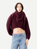 Close up of person wearing a burgundy sweater, wrapped a burgundy scarf and light blue jeans on a white background #color_burgundy