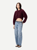 Person wearing a burgundy sweater and light blue jeans on a white background #color_burgundy
