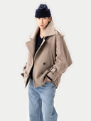 Person wearing a beige coat, black beanie, and blue jeans on a white background #color_taupe