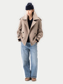Person wearing a beige coat, black beanie, black shirt, and blue jeans on a white background #color_taupe