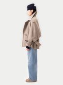 side view of Person wearing a beige coat and blue jeans on a white background #color_taupe