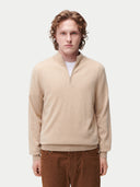 Man wearing a beige sweater and brown pants on a white background