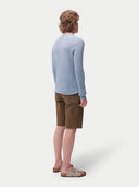 back view of a man wearing a light blue sweater and brown shorts on a white background. #color_celestial-blue