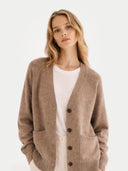 Woman wearing a brown v-neck cardigan over a white shirt on a light background #color_taupe