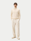 Man wearing a cream turtleneck sweater and pants on a white background #color_off-white