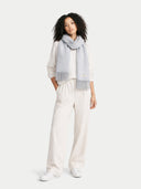 Woman wearing a light gray scarf and white pants on a white background #color_high-rise