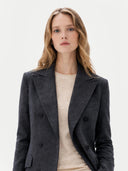 close up of a woman wearing a dark gray coat over a beige top on a light background #color_charcoal
