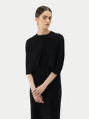 close up front view of a woman wearing a black lightweight silk cashmere capelet over a matching dress. #color_black