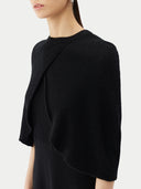 close up side view of a black short-length capelet over a black dress on a light gray background #color_black
