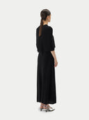Back view of a black short-length capelet over a black dress on a light gray background #color_black