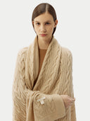 close up of a person wrapped in a beige cable knit blanket with a subtle pattern. #color_beige