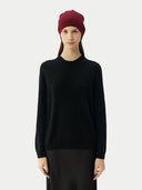 front view of a woman wearing a maroon beanie. a black sweater and silk skirt.