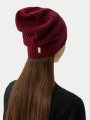 back view of a woman wearing a maroon beanie and a black sweater.