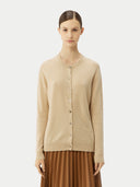 front view of a woman wearing a beige cashmere crew neck cardigan over a white top, paired with a brown pleated skirt. #color_beige