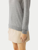close up of a gray sweater sleeve and beige skirt on a light gray background #color_vapor-blue