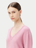 close up of a woman wearing a pink v-neck sweater