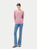 woman wearing a pink v-neck sweater and blue jeans