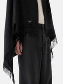 close up of a black fringed blanket with a black brand label "GOBI" and black pants #color_black