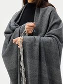 close up front view of a person wearing a gray striped blanket  with tassels on a white background #color_charcoal