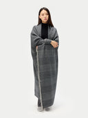 Woman wrapped in a long gray blanket against a white background #color_charcoal