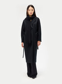 front view of a woman wearing a black double breasted coat and a scarf. #color_black