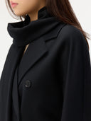close up of a woman wearing a black double breasted coat and a scarf. #color_black