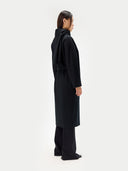 back view of a woman wearing a black double breasted coat and a scarf. #color_black